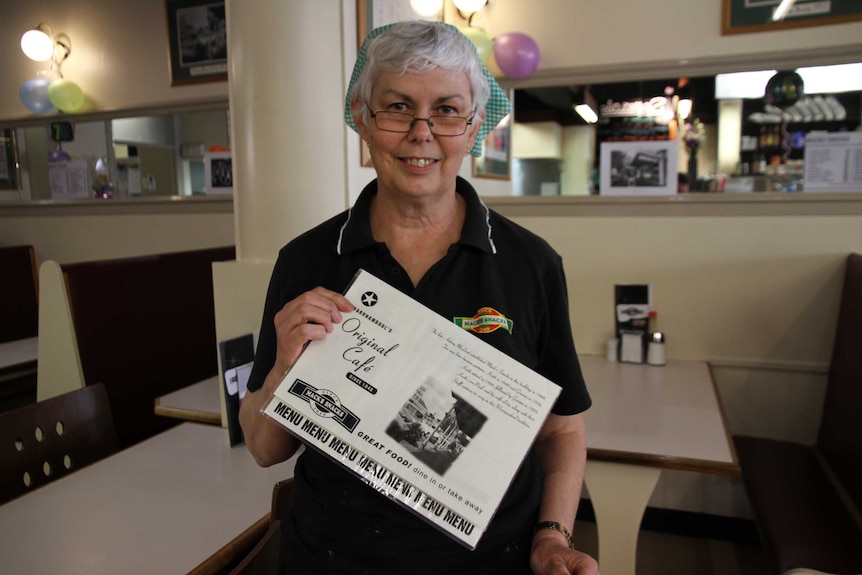 A cafe worker holds up an old-style menu.