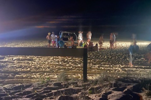 A group of people at the scene of a crash on Teewah Beach on Saturday where a Toyota Landcruiser rolled.