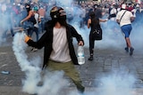 A protester throws a tear gas canister back at riot police during an anti-government protest.