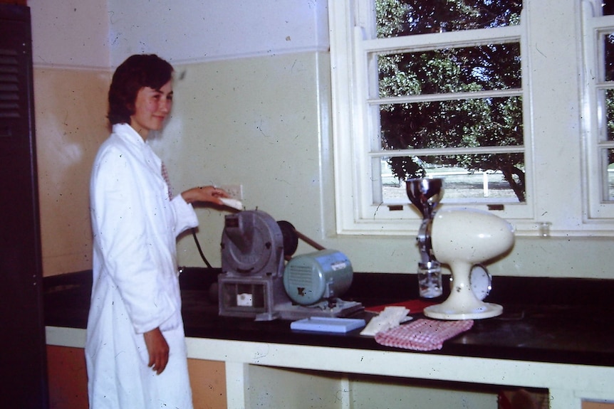 A woman wearing a white coat working in a lab.