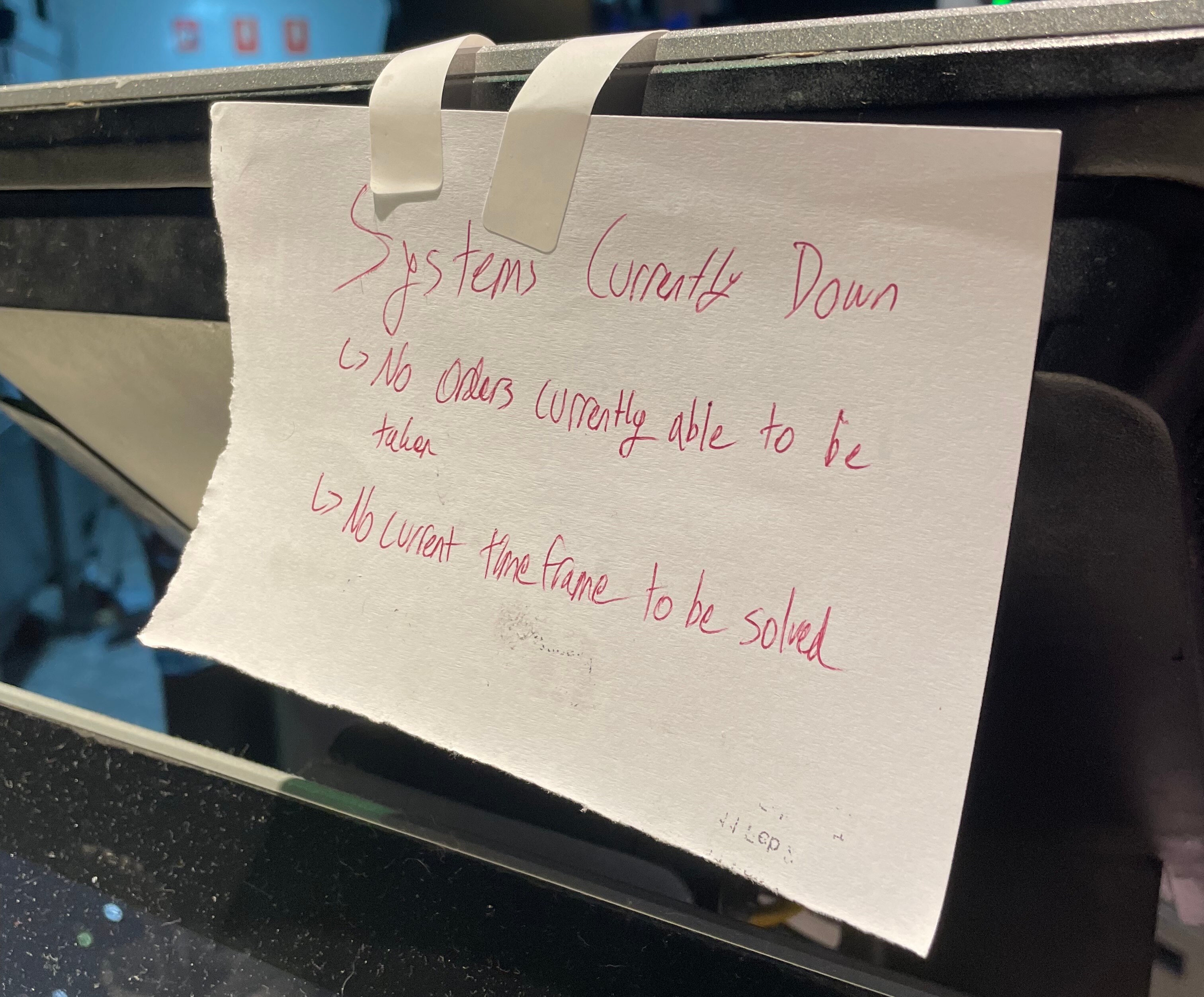 A piece of paper taped to a counter tells customers the system is currently down.