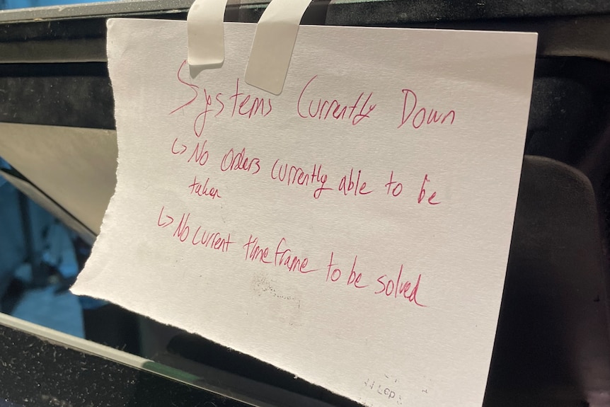 A piece of paper taped to a counter tells customers the system is currently down.