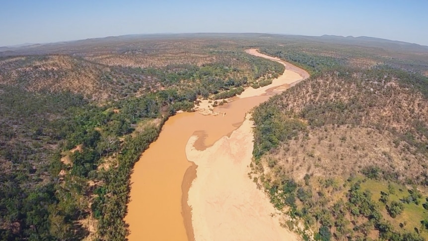 A large brown river snakes through outback cattle country.