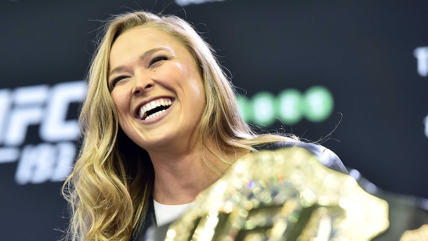 Ronda Rousey holds her title belt in Melbourne