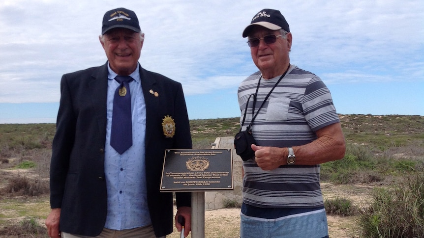 Two men stand near a commemorative plaque on the Montebello Islands