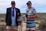Two men stand near a commemorative plaque on the Montebello Islands