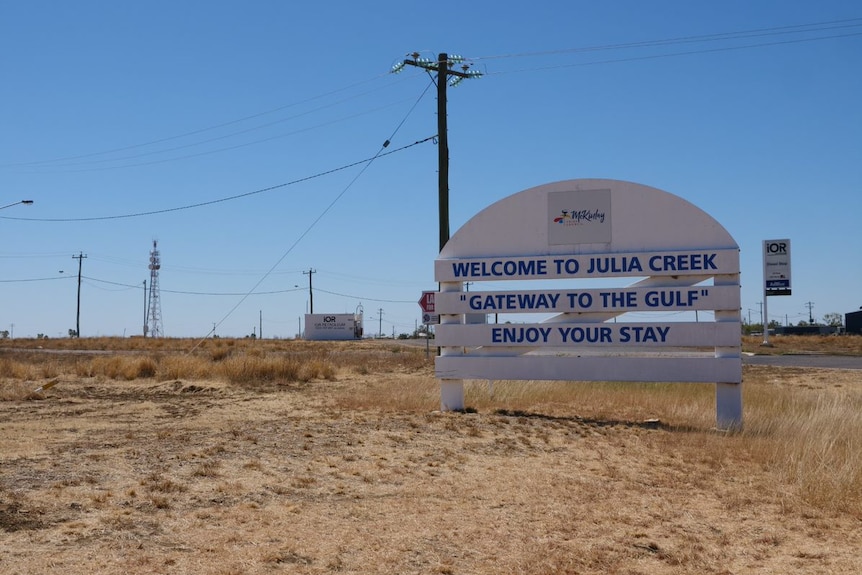 A white, rounded wooden sign that reads "Welcome to Julia Creek".