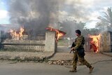 An Australian soldier walks past burning houses in Dili, East Timor.