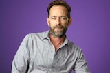Actor Luke Perry sits on a chair.