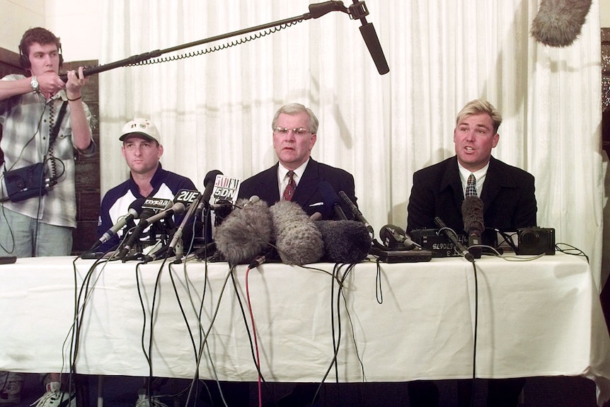 Mark Waugh, Malcolm Speed and Shane Warne sit at a table surrounded by microphones