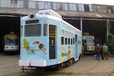 A picture of an old tram after being painted light blue and with pictures of animals