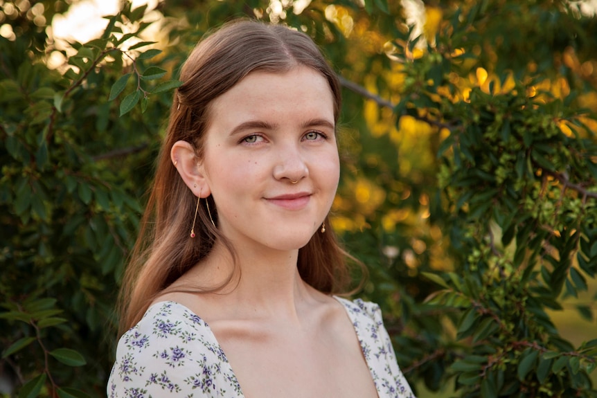 An image of a young woman in front of leafy background