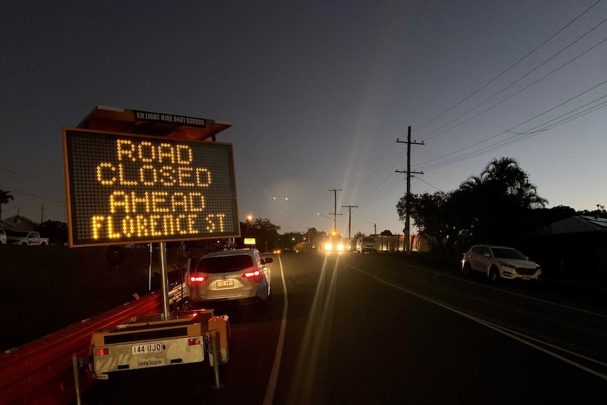 A road at night time with a sign that reads "road closed ahead of Florence St".