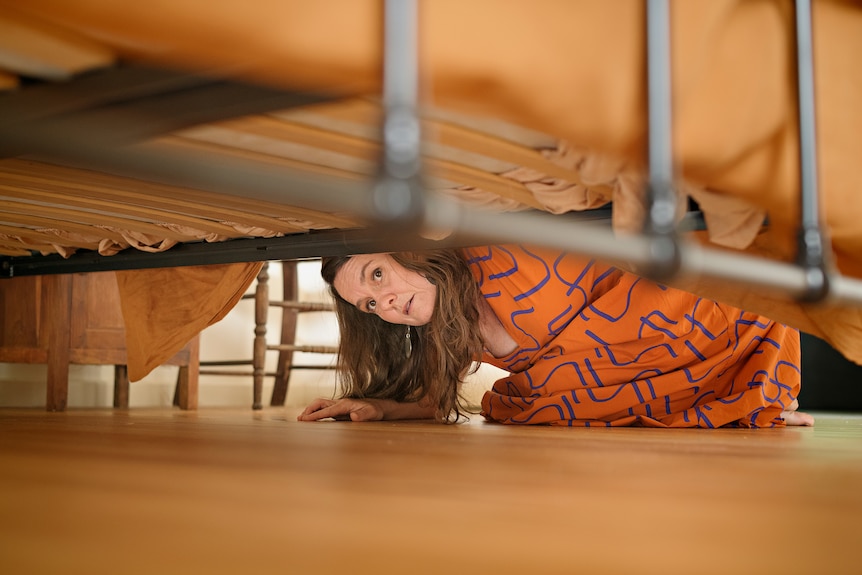 Sue Phoo looks under her bed in her Darwin home.
