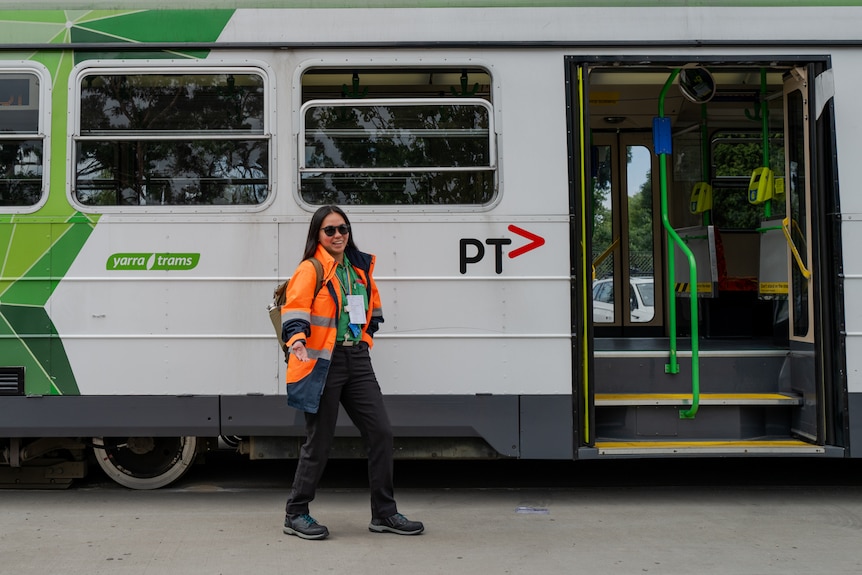 Patricia Santiago, a young woman of Filipino appearance, wears high-visibility clothes and drives a tram