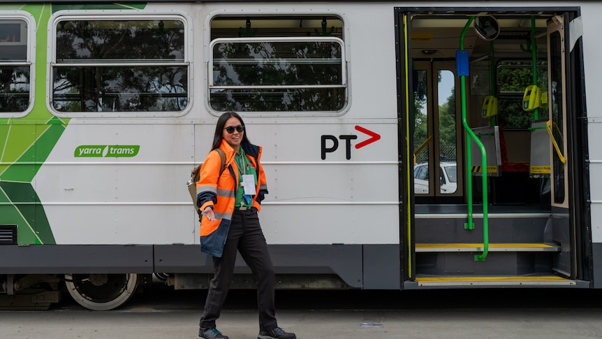Patricia Santiago, a young woman of Filipino appearance, wears high-visibility clothes and drives a tram