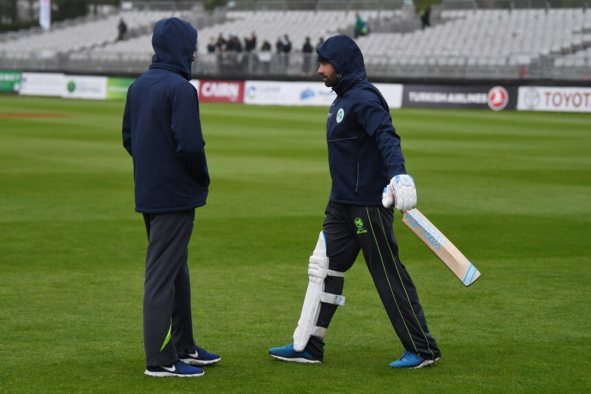 Two Irish batsmen wearing tracksuits with the hoods on.