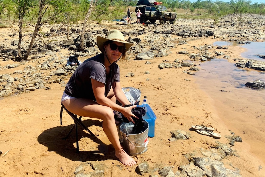 A woman washes clothes in a bucket.