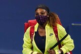 Serena Williams wears a facemask while walking past an on-court hoarding with her name on it