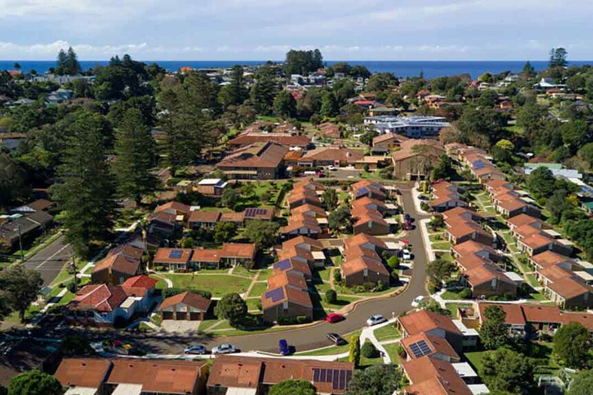 An aerial shot of a retirement village with rows of red-tiled roofs amid greenery.