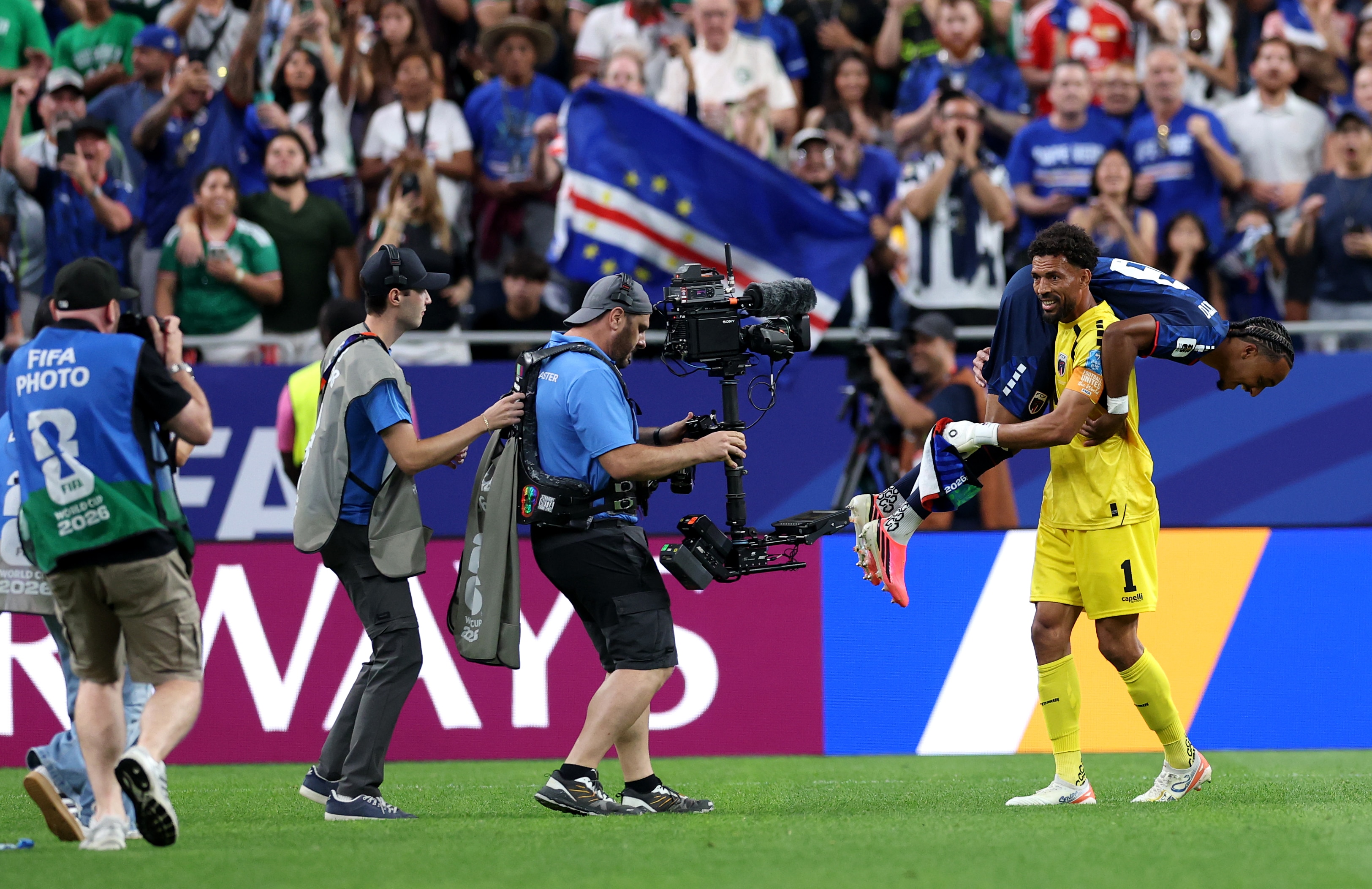 A goalkeeper lifts a teammate over his shoulders in celebration.
