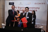 Two men shake hands while holding Chinese and Australian flags with Trade Minister Andrew Robb in the background