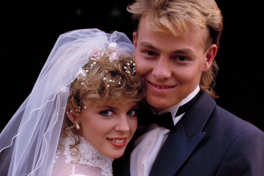 Kylie Minogue and Jason Donovan pose for a wedding photo while dressed as neighbors