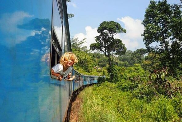 Girl leans out of a train window.