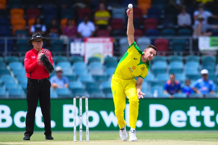 An Australian male bowler bowls against an Indian batter at Canberra's Manuka Oval.