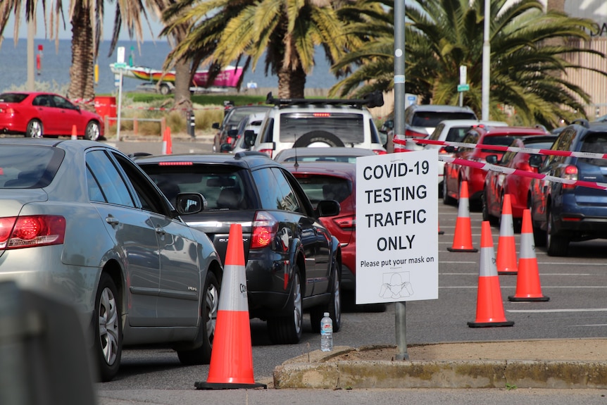 Two rows of cars move down the Palais Theatre carpark in aisles marked by orange traffic cones.