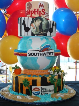 A tall cake surrounded by balloons.