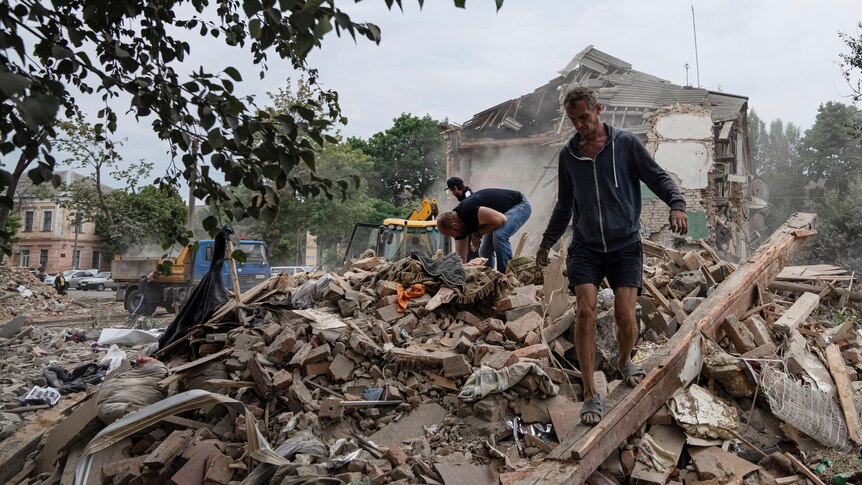 People search through the rubble of a destroyed building.