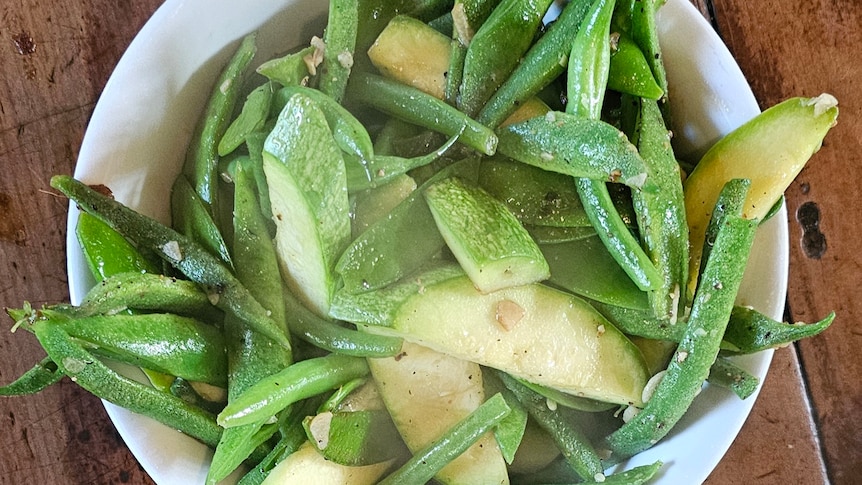Green salad in bowl with zucchini's, orange, beans