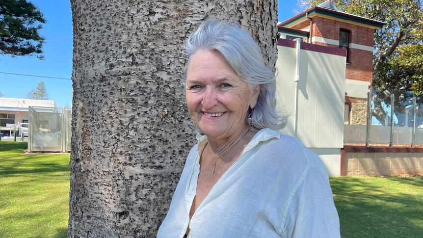 Grey haired woman smiling near tree