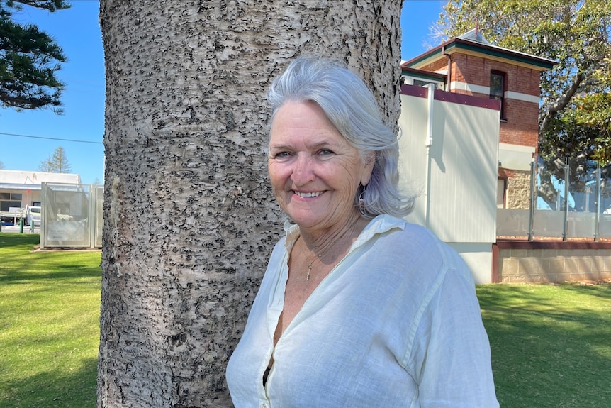 Grey haired woman smiling near tree