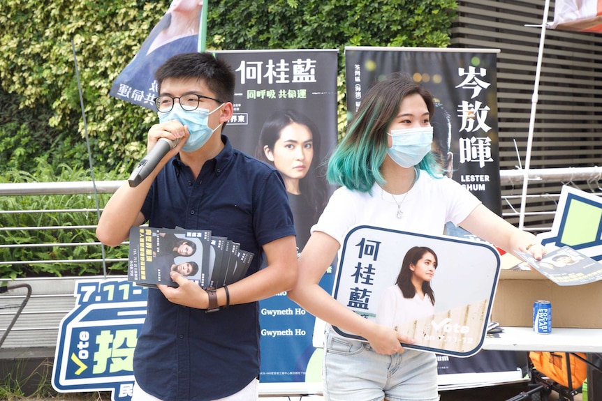 A man and a woman wearing masks and calling out in an election campaign.