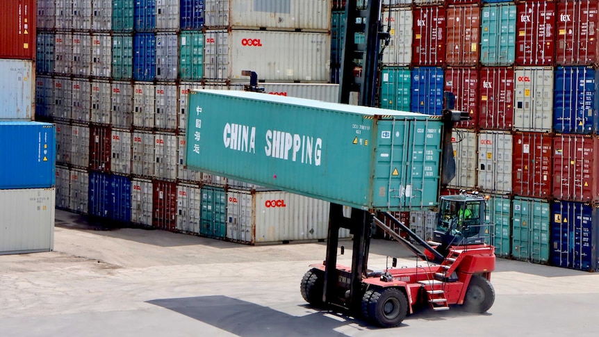 A forklift moves a China Shipping container at Port Botany, in front of a large stack of other containers.