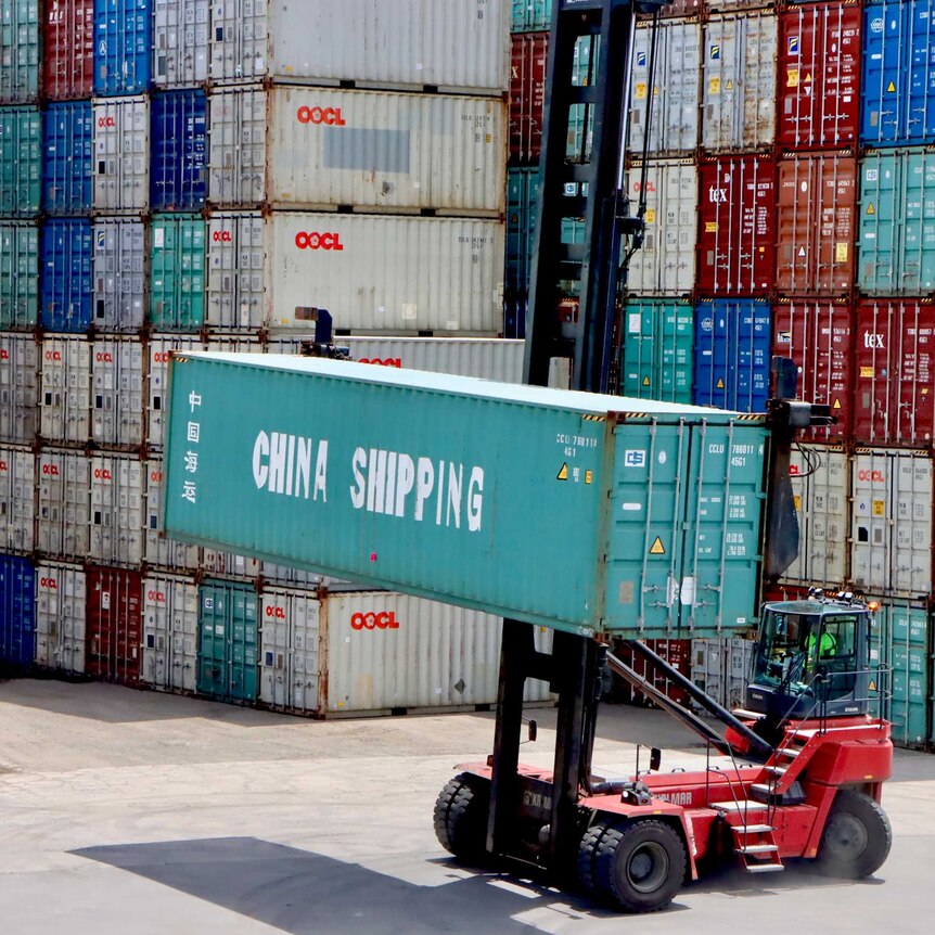 A forklift moves a China Shipping container at Port Botany, in front of a large stack of other containers.