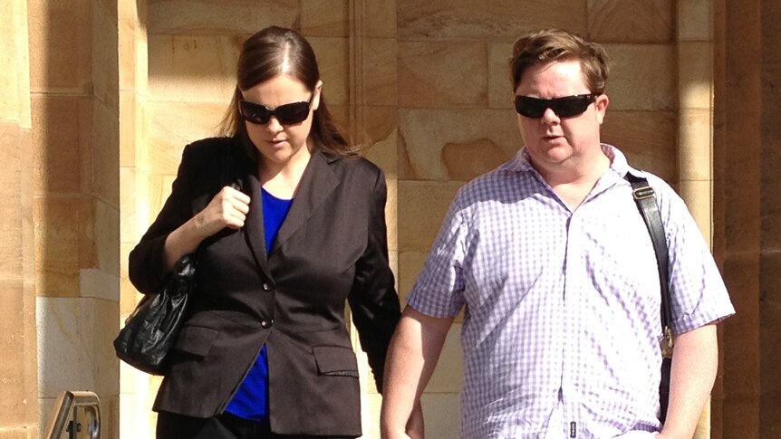 Kelly Nadene Schulz holds a man's hand as she walks outside Adelaide Magistrates Court.