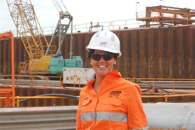 Jenny on a work site wearing an orange uniform and hard hat