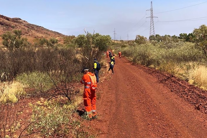 Emergency personnel search a red dirt road for Felicity Shadbolt