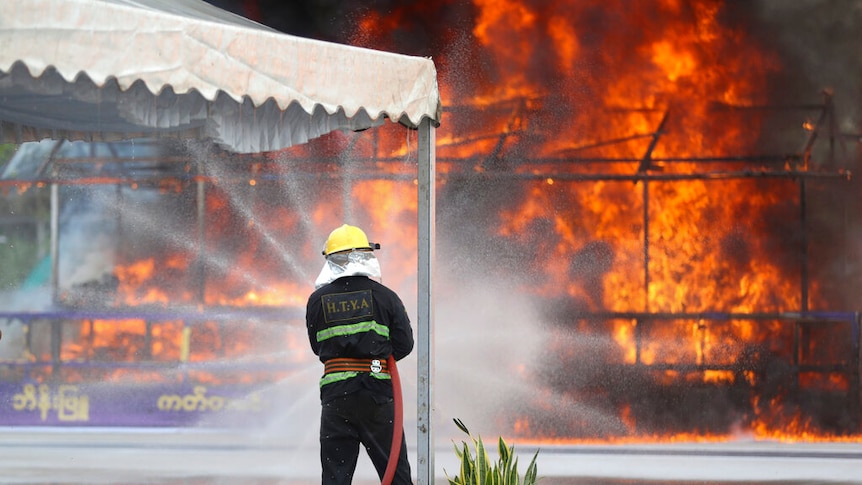 A firefighter sprays water on flames and smoke rising from burning illegal drugs during a destruction ceremony.