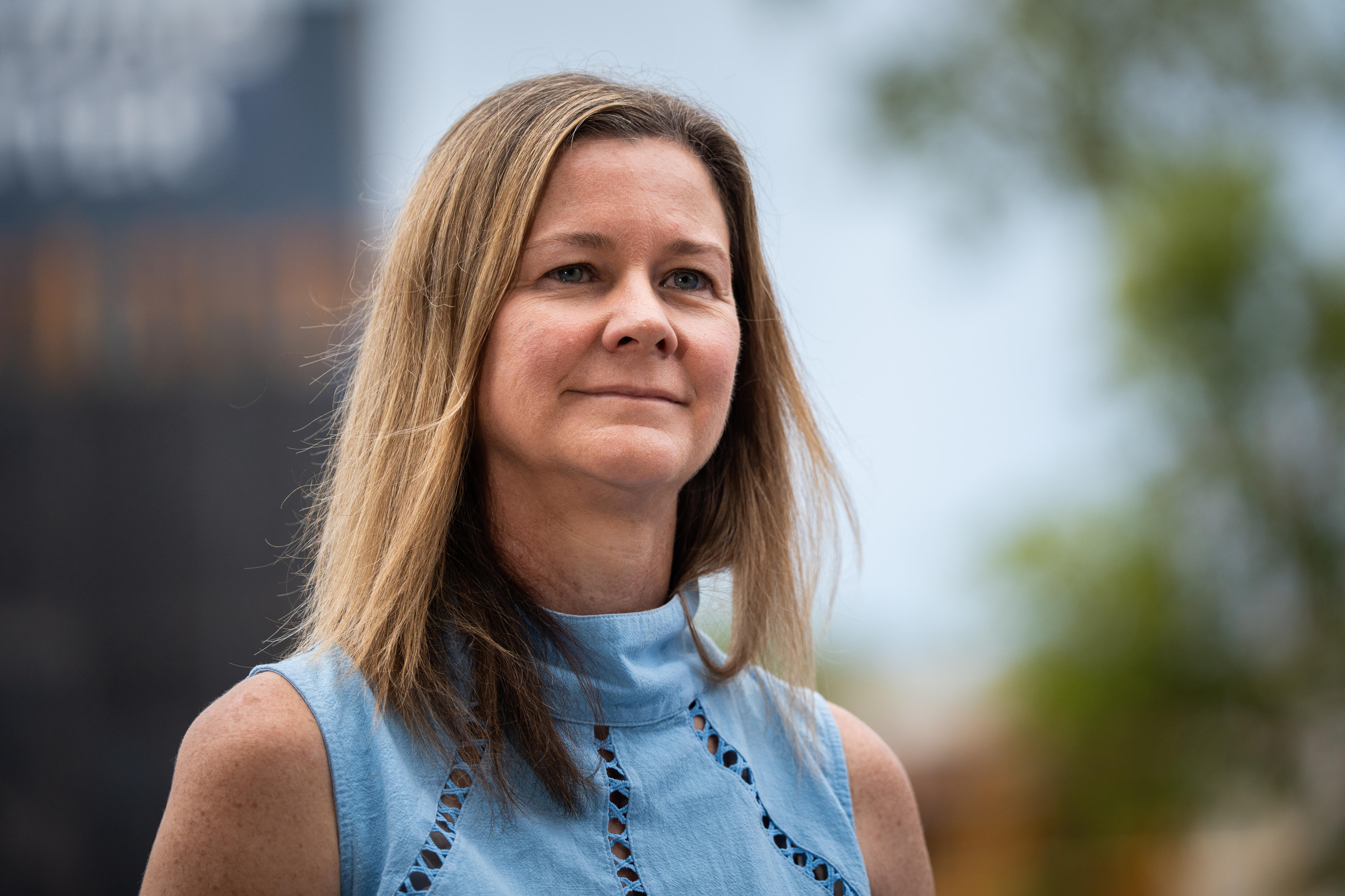 Uma mulher vestindo uma blusa azul, sorrindo.