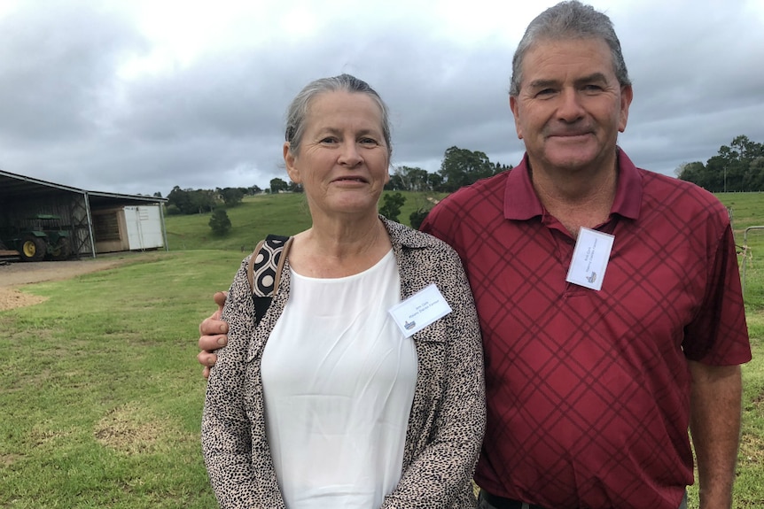 Anne and Rob Cork standing in front of green hills at Maleny Dairies.
