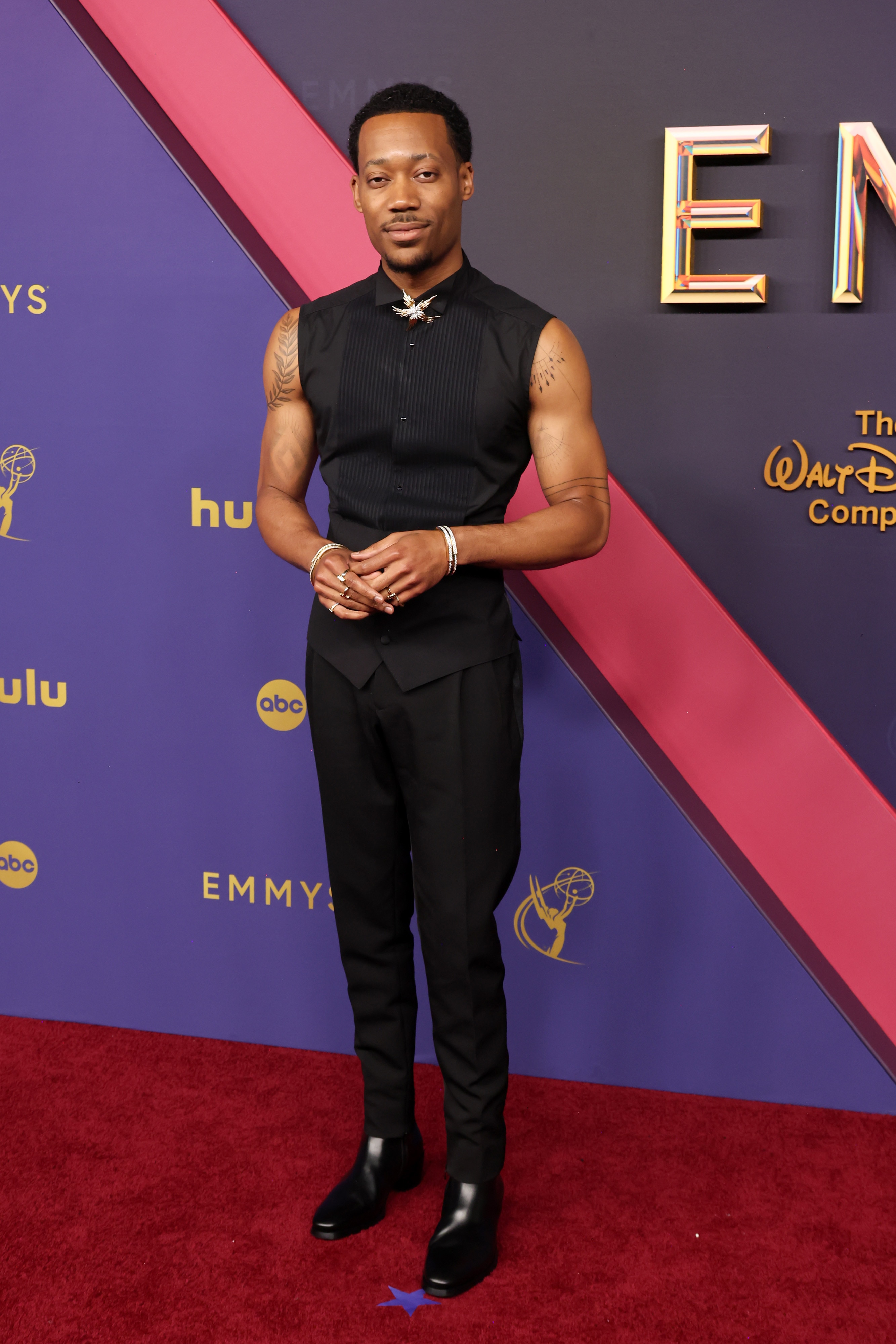 Tyler James Williams wearing a formal vest, clasped with a silvery, shimmery brooch 