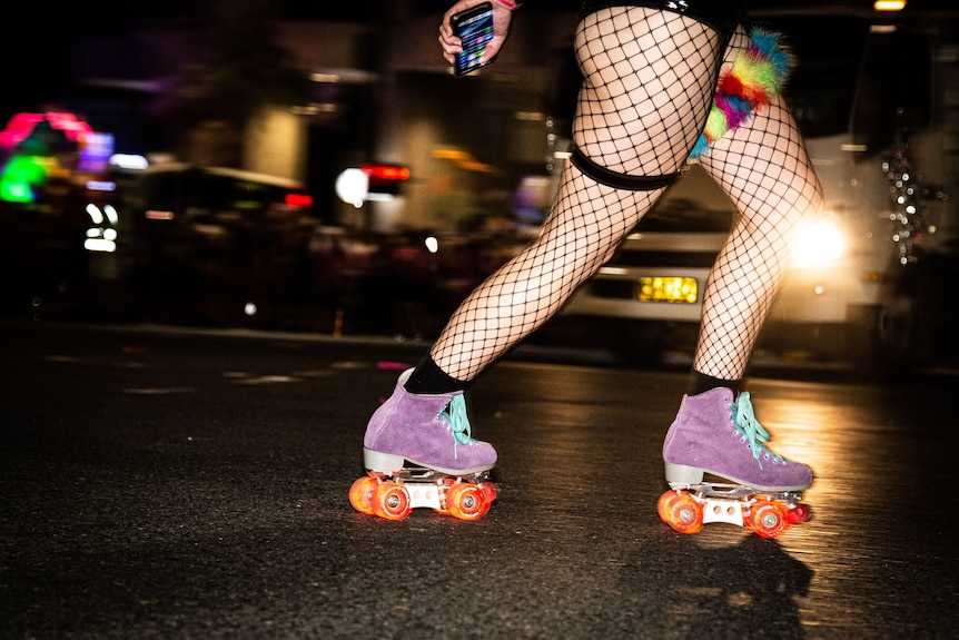 Photo shows the legs of a rollerskater dressed in fishnet stockings at night