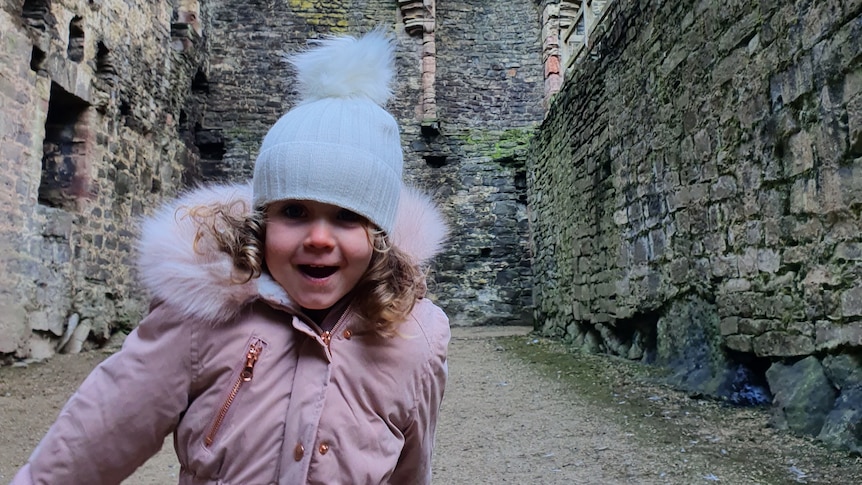 A little girl running and smiling inside a castle.