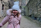 A little girl running and smiling inside a castle.