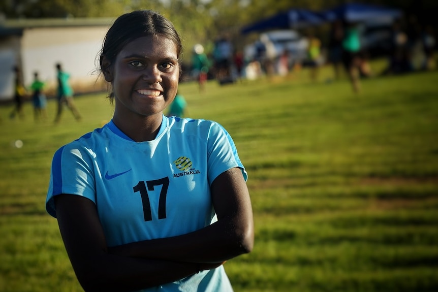 Shadeene Evans wears a light blue soccer shirt with the number 17 on it, and looks into the camera while standing on a field.