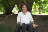 A man in a wheelchair looking at the camera.